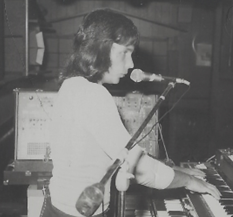 A young Dan Garrett singing and playing an ARP 2600 synthesizer on stage